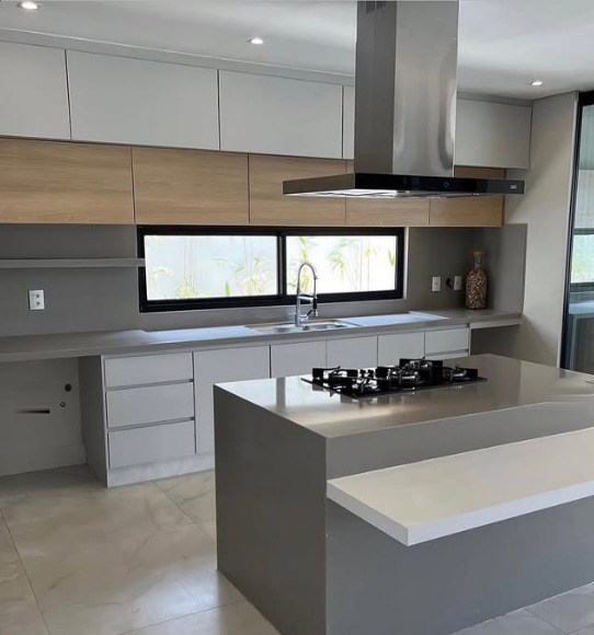 Cozinha com ilha em cinza, cooktop e aéreos amadeirados