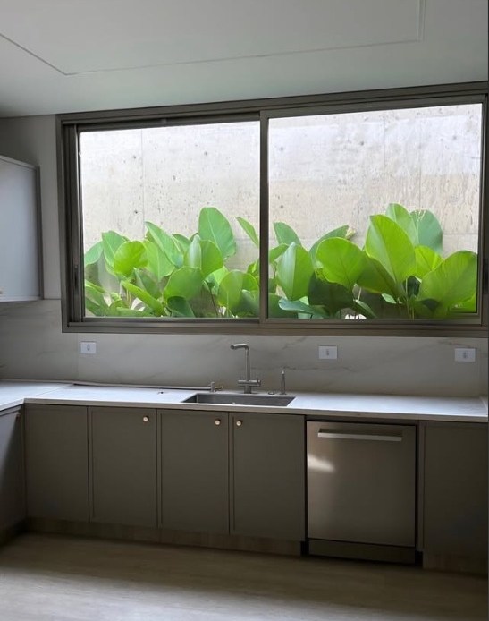Cozinha com armários em cinza sob janela ampla