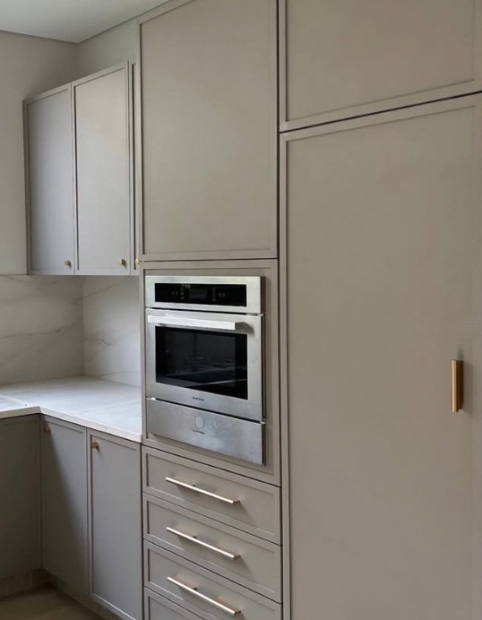 Cozinha em tom cinza com torre de forno, gaveteiro e ferragens douradas